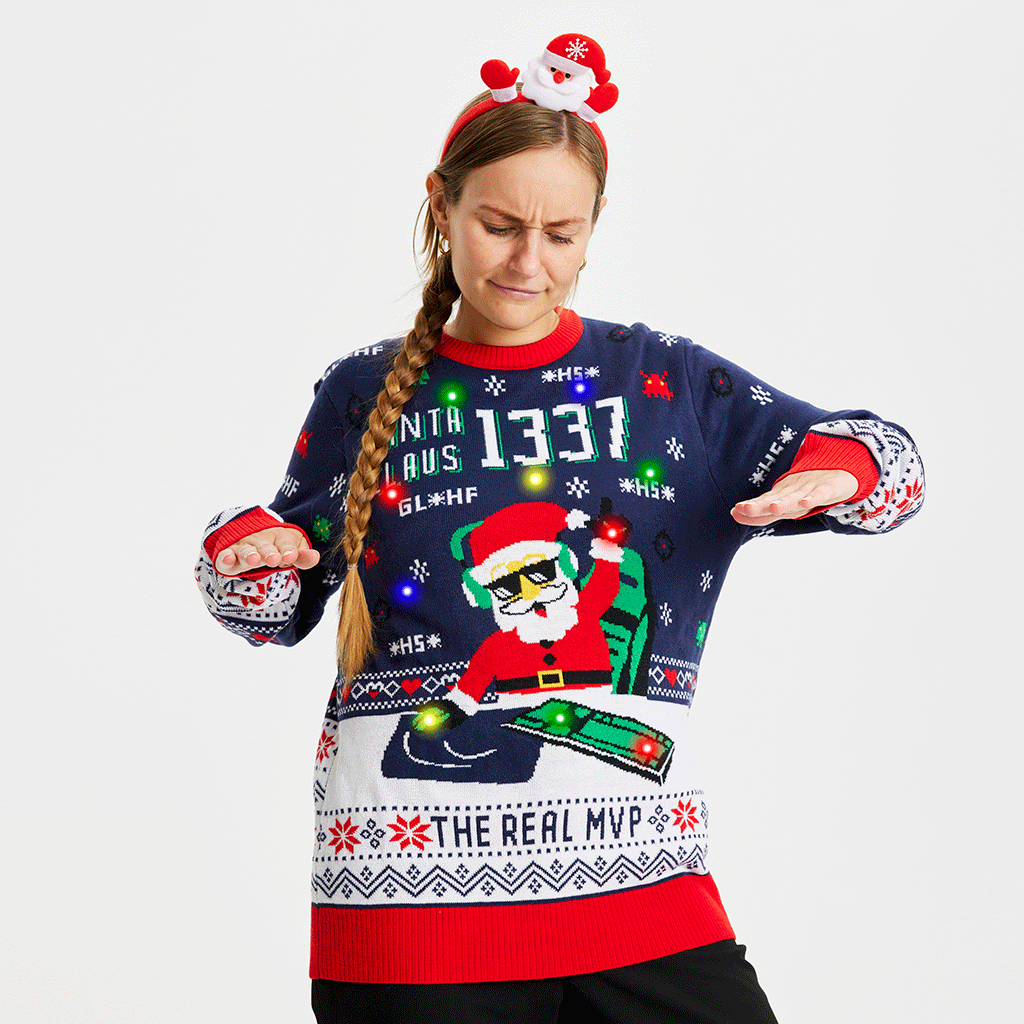 Une femme posant avec un pull de Noël bleu et rouge avec un Père Noël et des lumières.